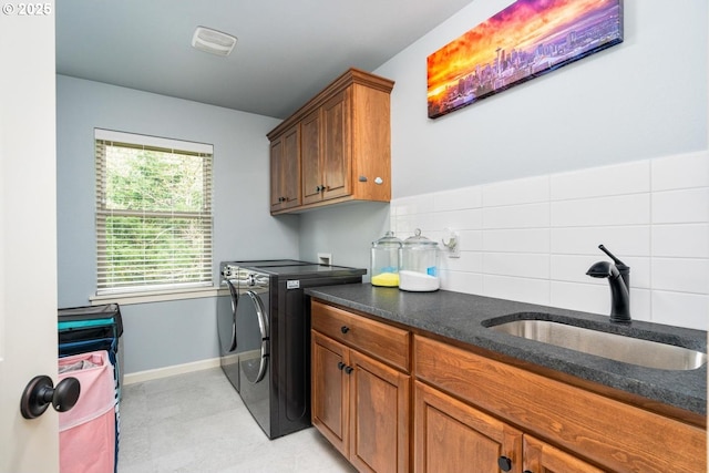 washroom with washing machine and dryer, cabinet space, baseboards, and a sink