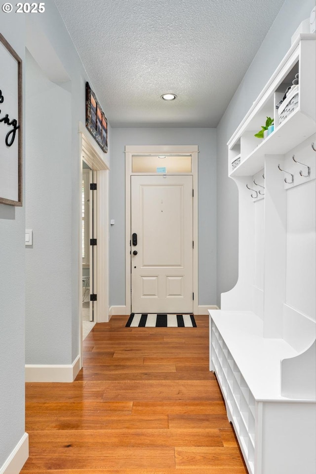 mudroom with a textured ceiling, baseboards, and light wood-style floors