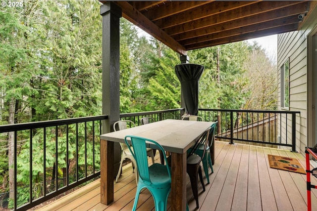 wooden deck with outdoor dining area and a view of trees