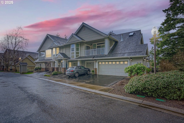 view of front of property with a garage, roof with shingles, driveway, and a balcony