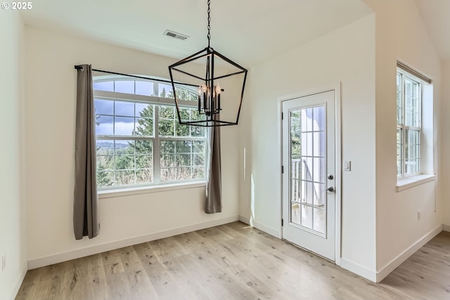 unfurnished dining area with light wood-style floors, a chandelier, visible vents, and baseboards