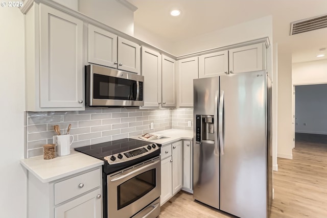 kitchen with tasteful backsplash, light countertops, visible vents, appliances with stainless steel finishes, and light wood-style floors