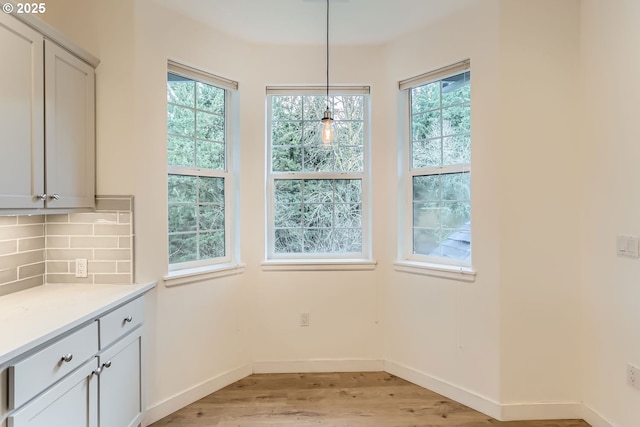 unfurnished dining area with light wood-style flooring and baseboards