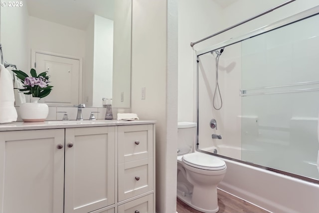 full bath featuring toilet, shower / bath combination with glass door, wood finished floors, and vanity