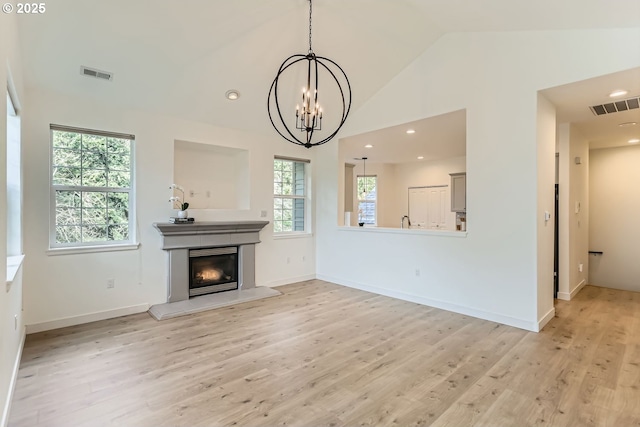 unfurnished living room with light wood finished floors, visible vents, and a glass covered fireplace