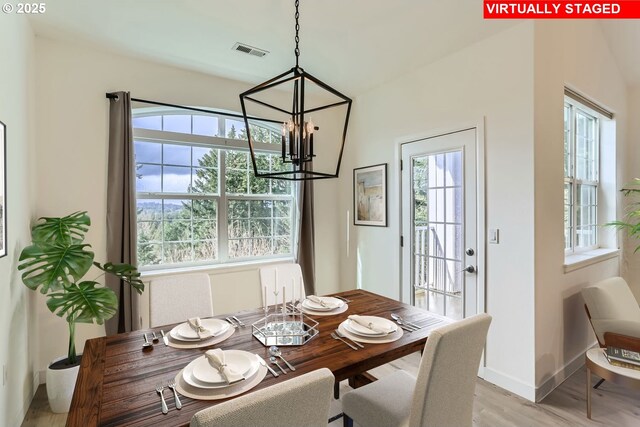 dining space featuring a chandelier, light wood finished floors, visible vents, and baseboards