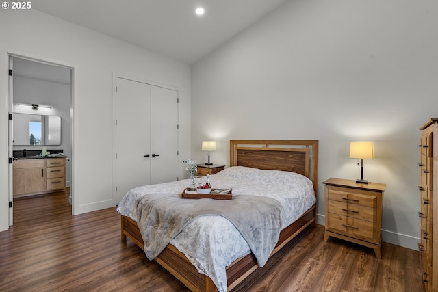 bedroom featuring lofted ceiling, ensuite bathroom, and dark hardwood / wood-style flooring