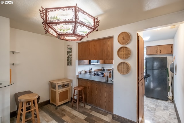 kitchen featuring range, hardwood / wood-style flooring, and black fridge