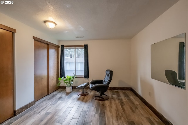 sitting room featuring a textured ceiling and light wood-type flooring