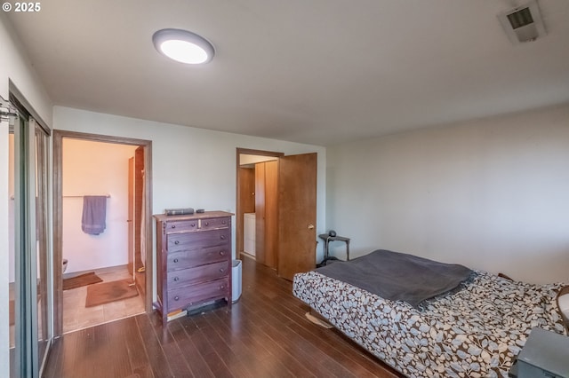 bedroom featuring ensuite bathroom and dark hardwood / wood-style flooring