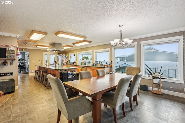 dining space featuring crown molding, a healthy amount of sunlight, and an inviting chandelier