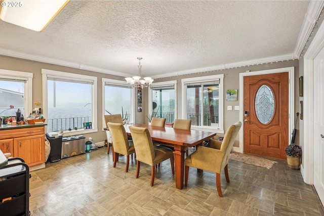 dining area featuring a notable chandelier, ornamental molding, and a textured ceiling