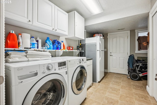 clothes washing area with separate washer and dryer, cabinets, and a textured ceiling