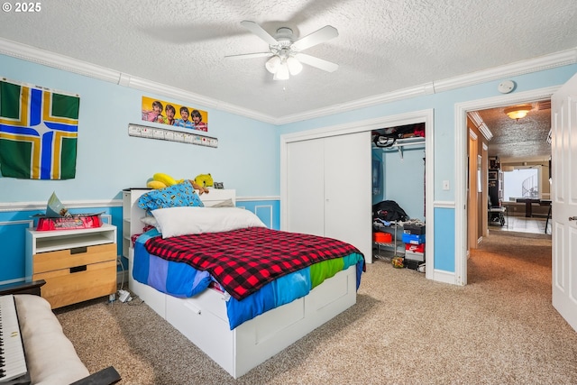 carpeted bedroom with crown molding, ceiling fan, a closet, and a textured ceiling