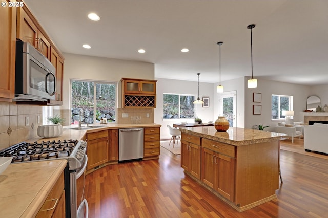 kitchen with decorative backsplash, stainless steel appliances, decorative light fixtures, and wood-type flooring