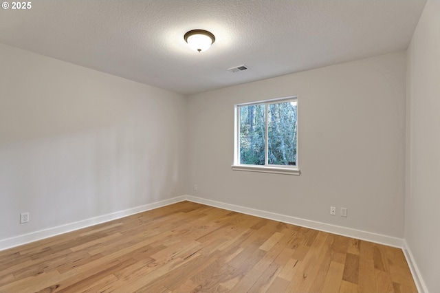 spare room featuring light hardwood / wood-style flooring and a textured ceiling