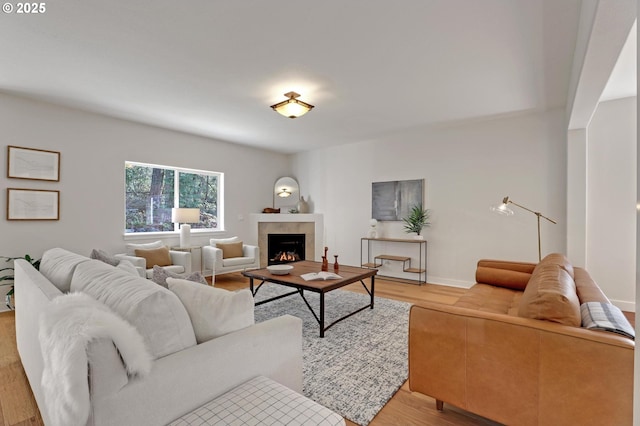 living room with a tile fireplace and light wood-type flooring