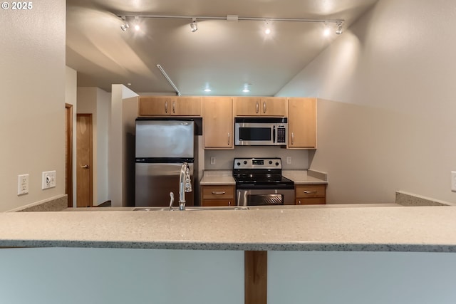 kitchen featuring appliances with stainless steel finishes, light countertops, a sink, and light brown cabinetry