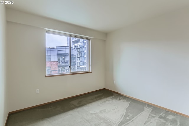 carpeted empty room featuring baseboards