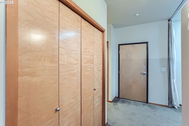 hallway featuring light carpet and baseboards