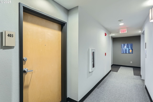 corridor featuring baseboards and light colored carpet