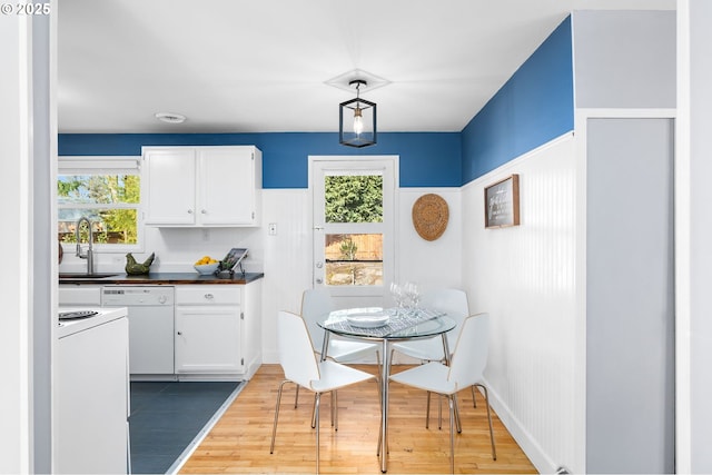 kitchen with sink, decorative light fixtures, white appliances, hardwood / wood-style floors, and white cabinets