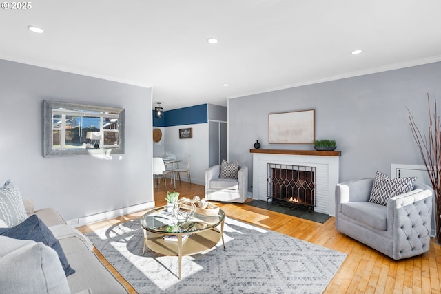 living room featuring hardwood / wood-style flooring, a baseboard radiator, a brick fireplace, and ornamental molding