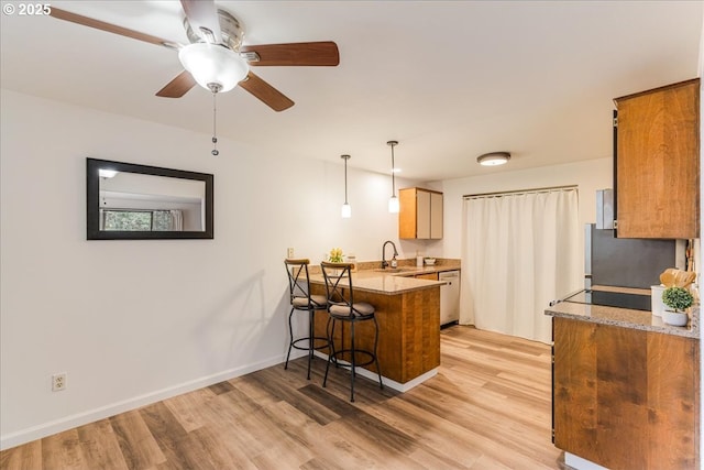 7148 SW Murray Blvd, Beaverton, OR 97008 - kitchen with a peninsula, light wood-style flooring, a sink, a kitchen breakfast bar, and ceiling fan