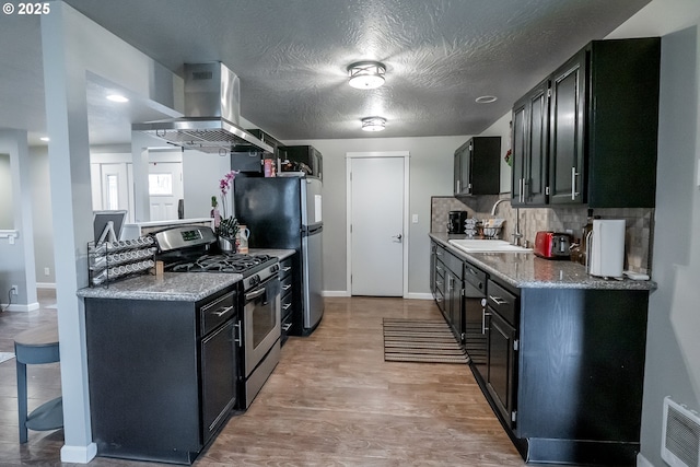 kitchen with light wood finished floors, decorative backsplash, island exhaust hood, stainless steel appliances, and a sink