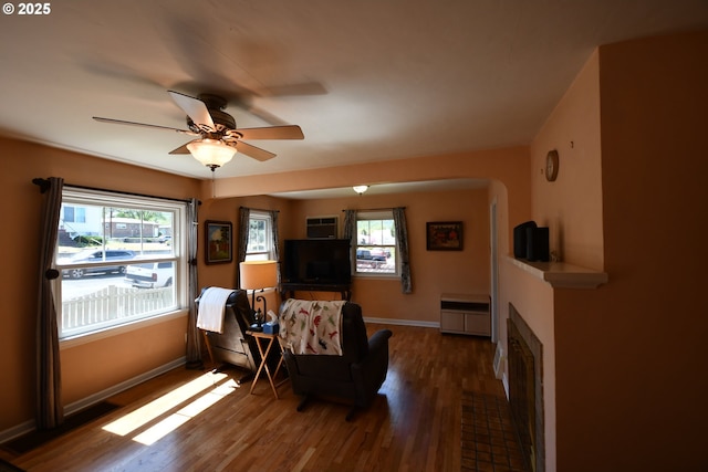 719 W 11th St, The Dalles, OR 97058 - sitting room featuring baseboards, ceiling fan, wood finished floors, arched walkways, and a fireplace