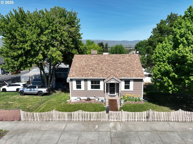 719 W 11th St, The Dalles, OR 97058 - new england style home featuring a front lawn, a fenced front yard, and a chimney