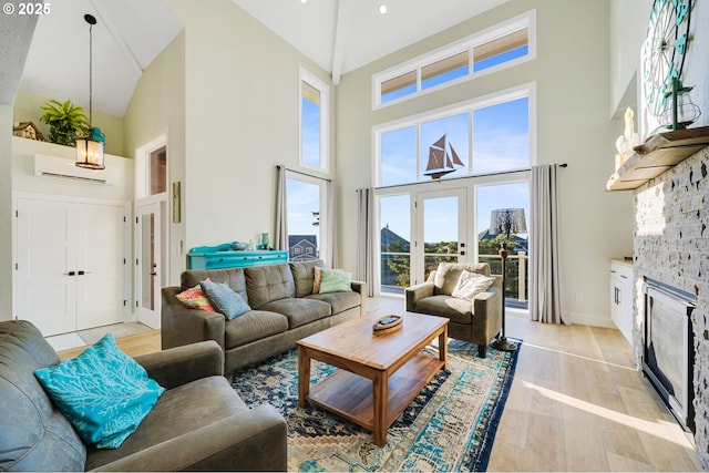 living area featuring light wood-style floors, high vaulted ceiling, baseboards, and a fireplace