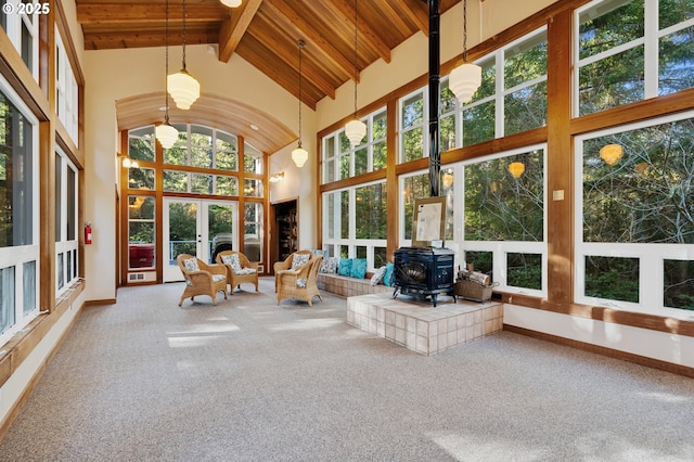 sunroom with french doors, a wood stove, and beam ceiling