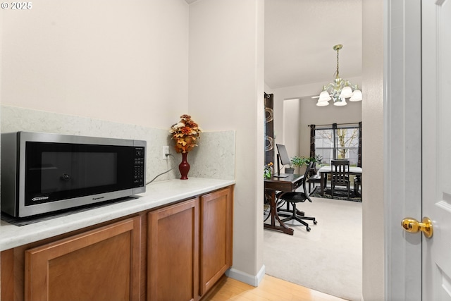 20053 SW 54th Ter, Tualatin, OR 97062 - bar area featuring stainless steel microwave, a chandelier, light wood-style flooring, hanging light fixtures, and baseboards