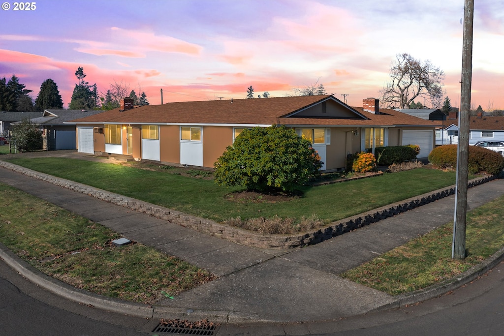 ranch-style home with a garage and a yard