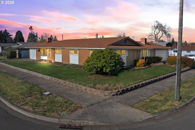 ranch-style home with a garage and a yard