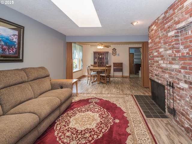 19838 NE Wasco St, Portland, OR 97230 - living room featuring wood finished floors, a skylight, a brick fireplace, and a textured ceiling