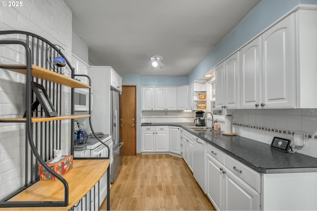 kitchen with sink, light hardwood / wood-style flooring, white dishwasher, white cabinets, and decorative backsplash