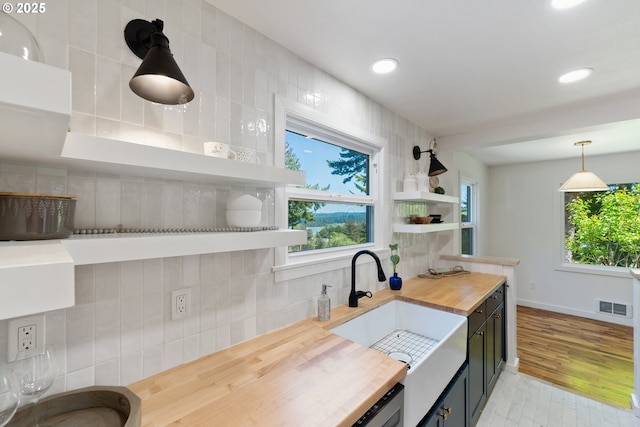 kitchen with wooden counters, visible vents, tasteful backsplash, open shelves, and a sink