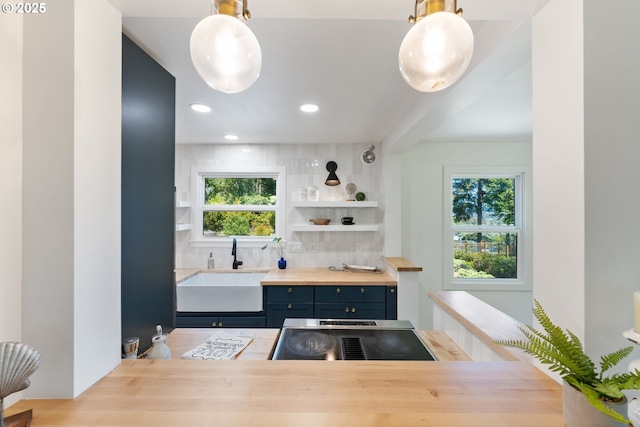 kitchen featuring open shelves, tasteful backsplash, a sink, wood counters, and blue cabinetry