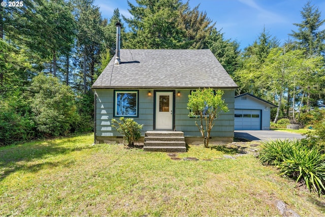 bungalow-style home with a detached garage, an outbuilding, a shingled roof, and a front lawn