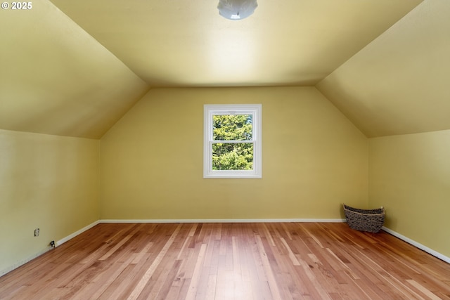 additional living space featuring baseboards, vaulted ceiling, and hardwood / wood-style floors