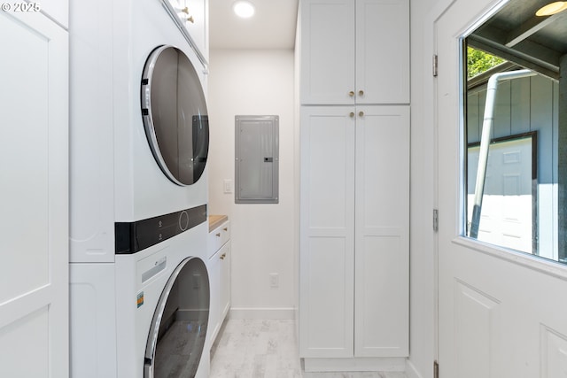 washroom featuring electric panel, stacked washer / dryer, cabinet space, baseboards, and recessed lighting