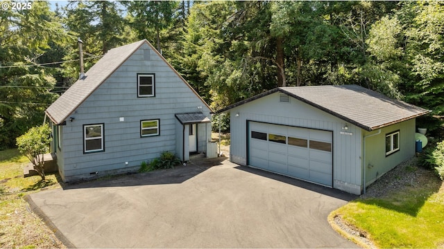 view of front of home featuring crawl space, roof with shingles, a detached garage, an outdoor structure, and aphalt driveway
