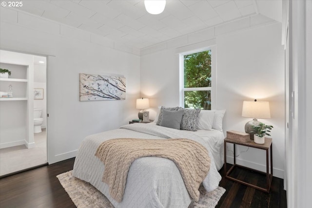 bedroom featuring ensuite bathroom and dark hardwood / wood-style floors