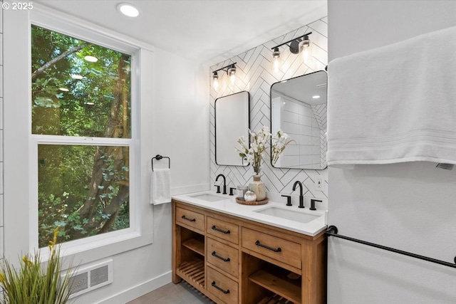 bathroom featuring vanity, decorative backsplash, and a healthy amount of sunlight