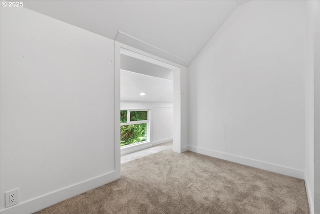 carpeted empty room with vaulted ceiling