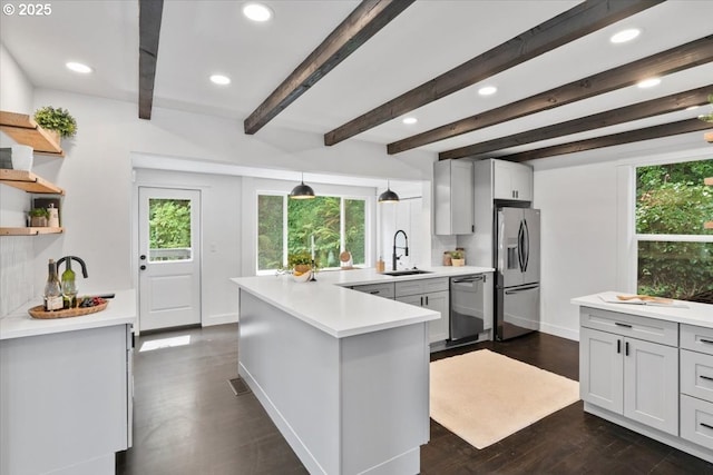 kitchen with appliances with stainless steel finishes, dark wood-type flooring, pendant lighting, beam ceiling, and sink