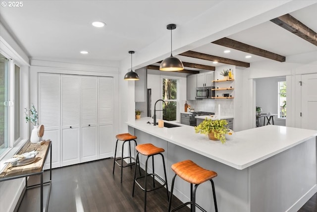 kitchen featuring kitchen peninsula, hanging light fixtures, beam ceiling, a breakfast bar, and sink