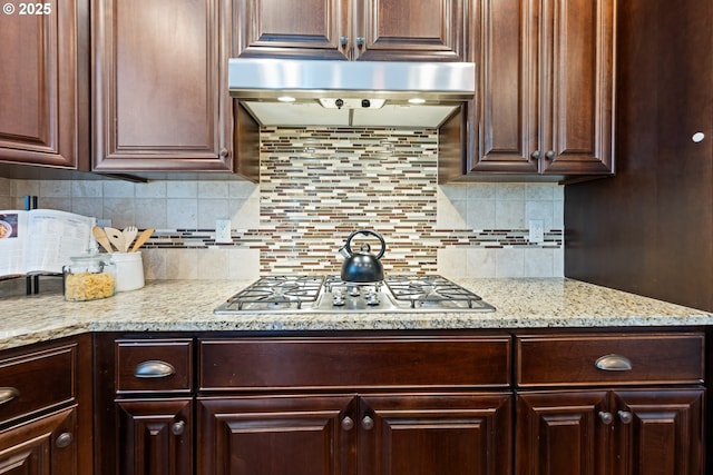 17007 NW Reuben Ln, Portland, OR 97229 - kitchen featuring stainless steel gas stovetop, under cabinet range hood, dark brown cabinets, backsplash, and light stone counters